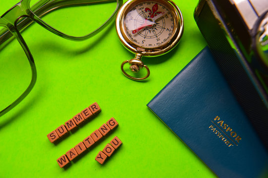 Summer waiting you message written on wooden blocks,. passport, smartphone, eyeglass, analog camera isolated green background