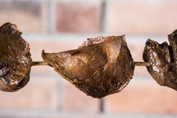 anticuchos, Peruvian cuisine, meat heart veal skewered on the grill with the background of a brick wall.