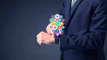 Businessman wearing smartwatch with colored application symbols on it.