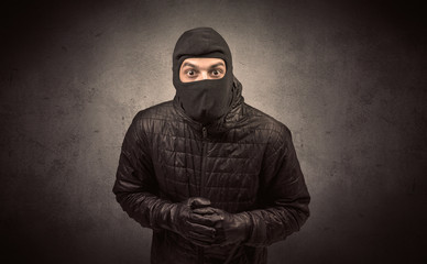 Burglar standing in black clothes and balaclava on his head.