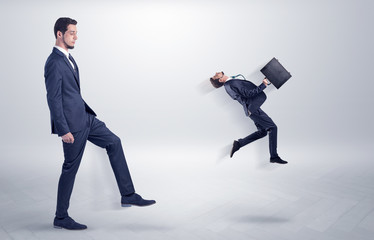 Small young man fired by his bos from his workplace with suitcase on his hand
