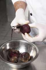 the chef cleans the red beet in the kitchen of the restaurant over a metal plate