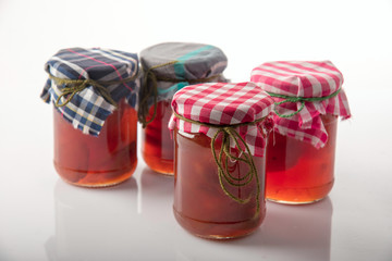 jam in jars with fabric covers on white background