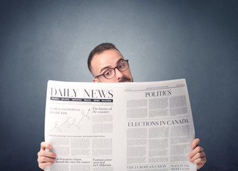 Young smart businessman reading daily newspaper