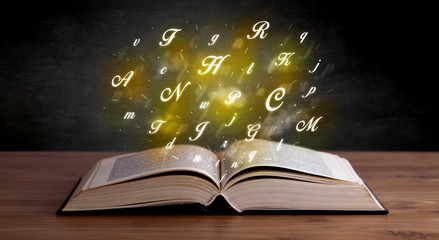 Glowing yellow alphabet letters coming out of an open book 