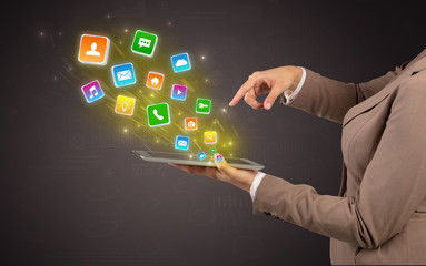 Hand holding tablet and application icons falling inwards
