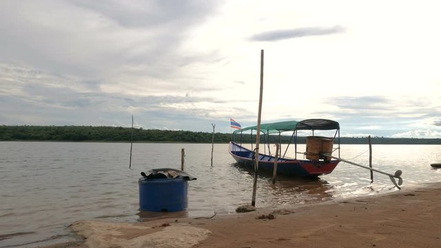 The old boat on the beach of reservoir dam big river against forest with sunset afternoon ambient