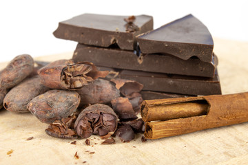 Tasty dark chocolate and cocoa beans on a white table. Sweets used to prepare desserts in the kitchen.