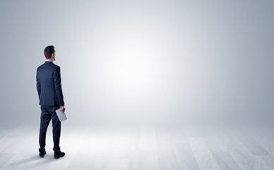 Man standing with his back in an empty room with object in his hand