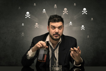 Loser drunk man sitting at table with skulls concept around
