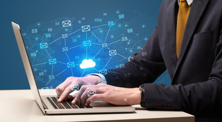 Businessman hand sending a bunch of messages on laptop with cloud computing concept
