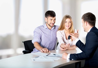 Happy couple with car dealer in auto show or salon