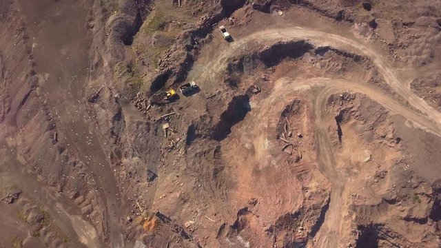 Aerial view of working excavator in the opencast mine. Camera flight over industrial landscape.