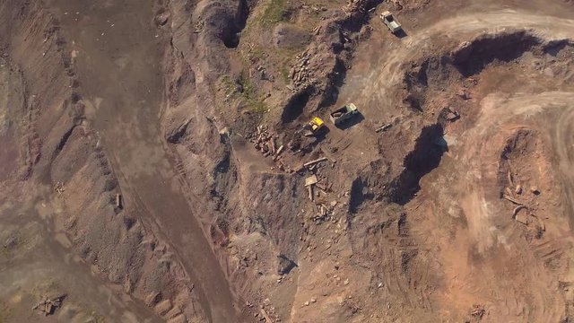 Aerial view of working excavator in the opencast mine. Camera flight over industrial landscape.