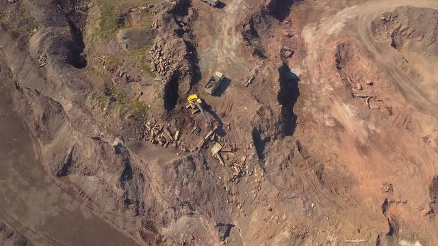 Aerial view of working excavator in the opencast mine. Camera flight over industrial landscape.