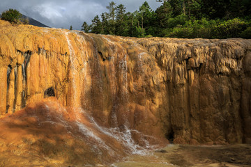Waterfall in Huanglong Scenic Area in Sichuan Province, China. Water flowing over beautiful exotic natural yellow geological landforms, erosion over time. Chinese Yellow Dragon Terraces, National Park