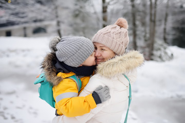 Mother or grandmother with her little son or grandson embrace in winter day