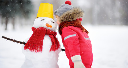 Little boy tell snowman about his secrets or gifts for Christmas
