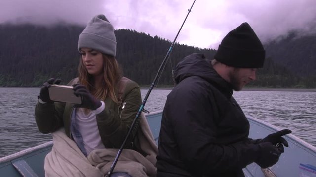 Couple taking pictures on boat and preparing fishing pole