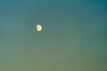 The moon against the blue sky. The moon by day.
