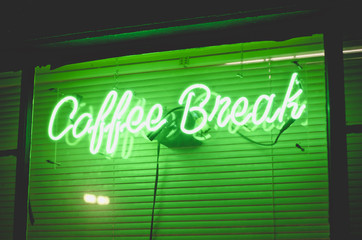 The green neon light sign of the local coffee break in downtown utah. 