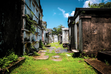 General angled view of old antique cemetery with raised crumbling sepulchers and blue skies