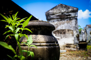 General angled view of old antique cemetery with raised crumbling sepulchers and blue skies