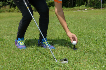 Asian golf girl put golf on tee in green golf course