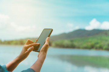 Woman hand using smartphone or tablet to do business in park outdoor nature road background.