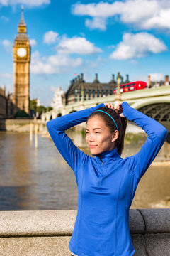 London fitness sport athlete getting ready for run workout tying hair into ponytail with headband and hair ties at Big Ben westminster travel destination. UK marathon training.