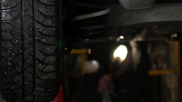 Car service - bottom of the car on a lift at a workshop. 4K