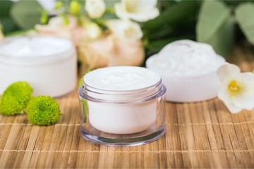 Fototapeta na wymiar Cosmetic cream with white flowers on table
