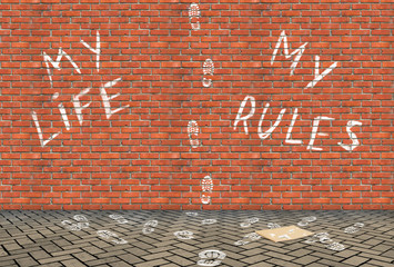 Footprints going upwards on a high brick wall and text My Life My Rules