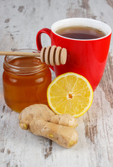 Fresh lemon with honey and cup of tea on wooden table