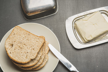 Plate with toasts and butter on dark table