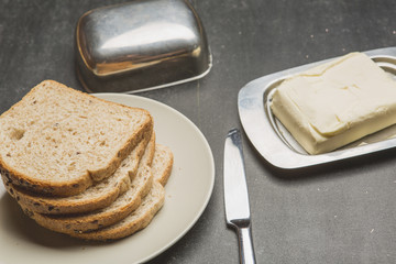 Plate with toasts and butter on dark table