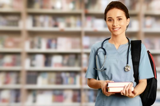 Attractive young female medical student with backpack and books