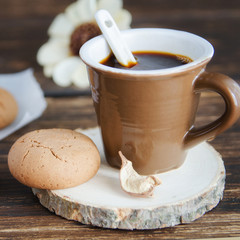 Cup of black coffee and almond cookies and fall leaves on wooden table. Delicious beverage for cold autumn season. Good morning concept.