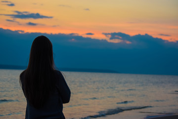 girl looks at dramatic clouds over the river