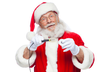 Christmas. Santa Claus in white gloves holding a soldering iron with a solder. Electronics,...
