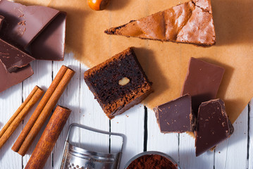chocolate brownie cake and ingredients, baking papaer on white wood table background