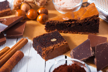 chocolate brownie cake and ingredients, baking papaer on white wood table background