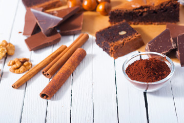 chocolate brownie cake and ingredients, baking papaer on white wood table background