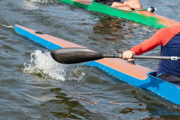 Photo of a part of a kayak with a paddle and a rower.