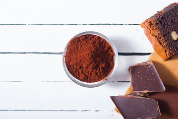 chocolate brownie cake and ingredients, baking papaer on white wood table background