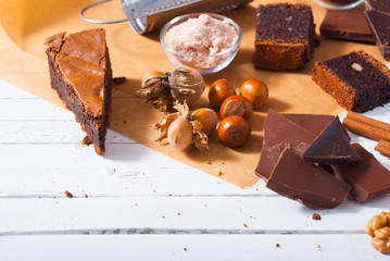 chocolate brownie cake and ingredients, baking papaer on white wood table background