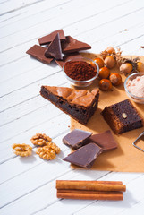 chocolate brownie cake and ingredients, baking papaer on white wood table background