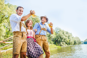 Oktoberfest Freunde in Lederhosen und Dirndl trinken Bier an der Isar