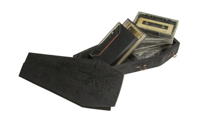 Audio cassettes in black coffin isolated on white background / Obsolete technology of music tape