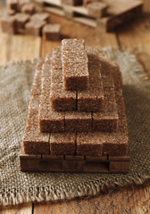 golden pyramid of brown sugar cubes on wooden background